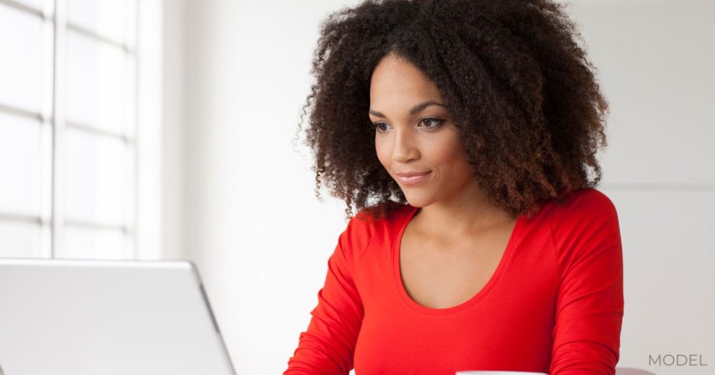 A woman thinking while looking at a computer (model)